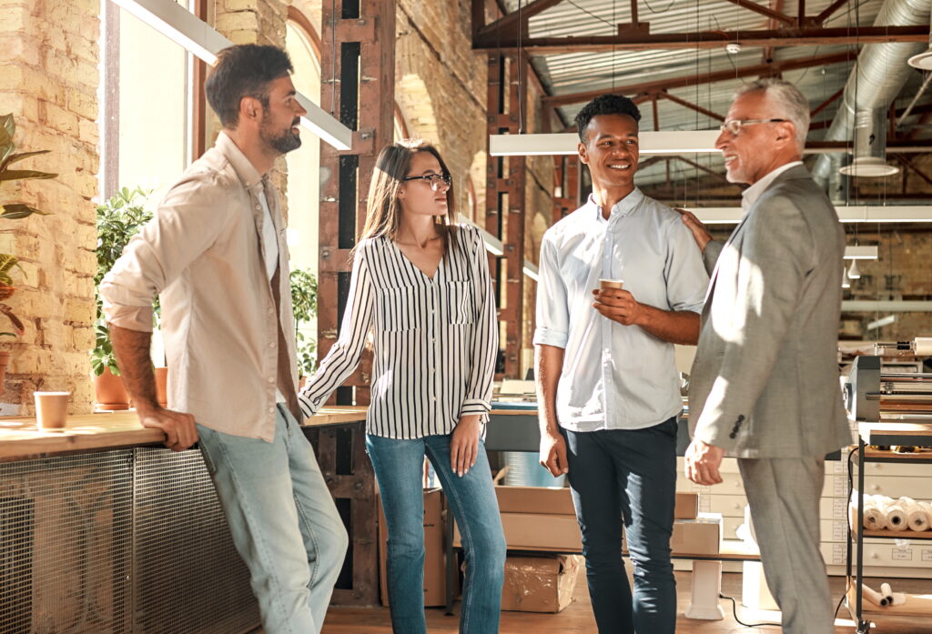 Boomer Mentoring: Erfahrener Unternehmer im Gespräch mit jungen Gründern in einem modernen Co-Working-Space